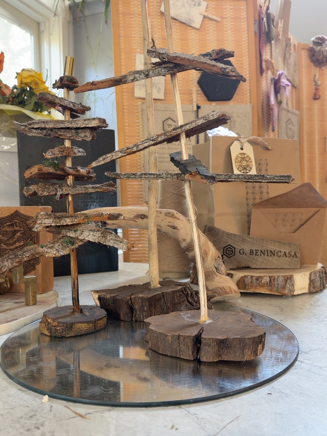 Bark pieces arranged in tiers around upright rods on wood-round bases, standing on a circular mirrored tray in the studio.